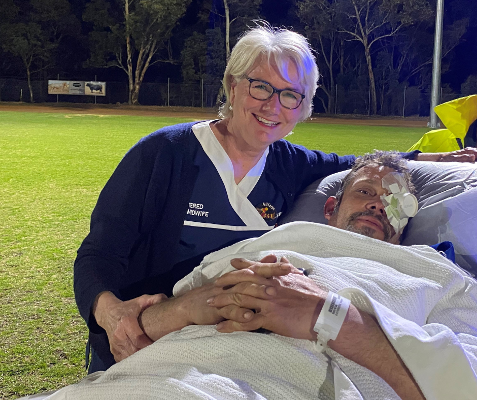 Nurse next to man on a stretcher outside at night in a field