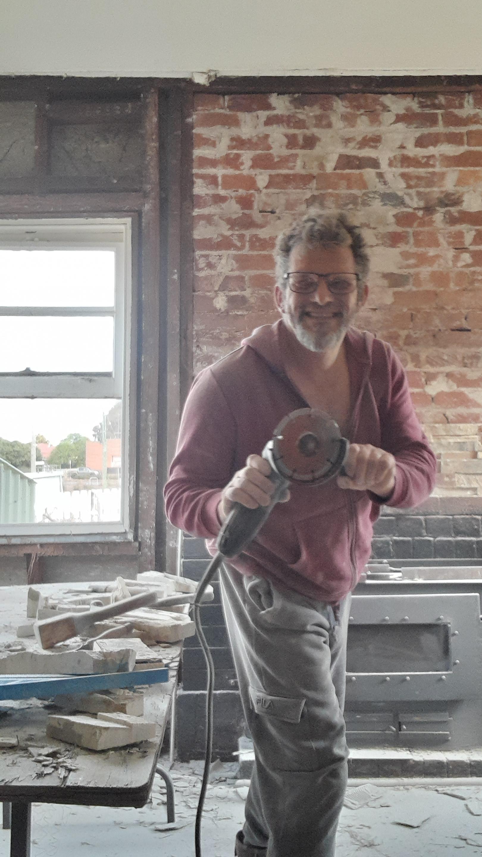 Man with a power tool in a brick-walled interior room