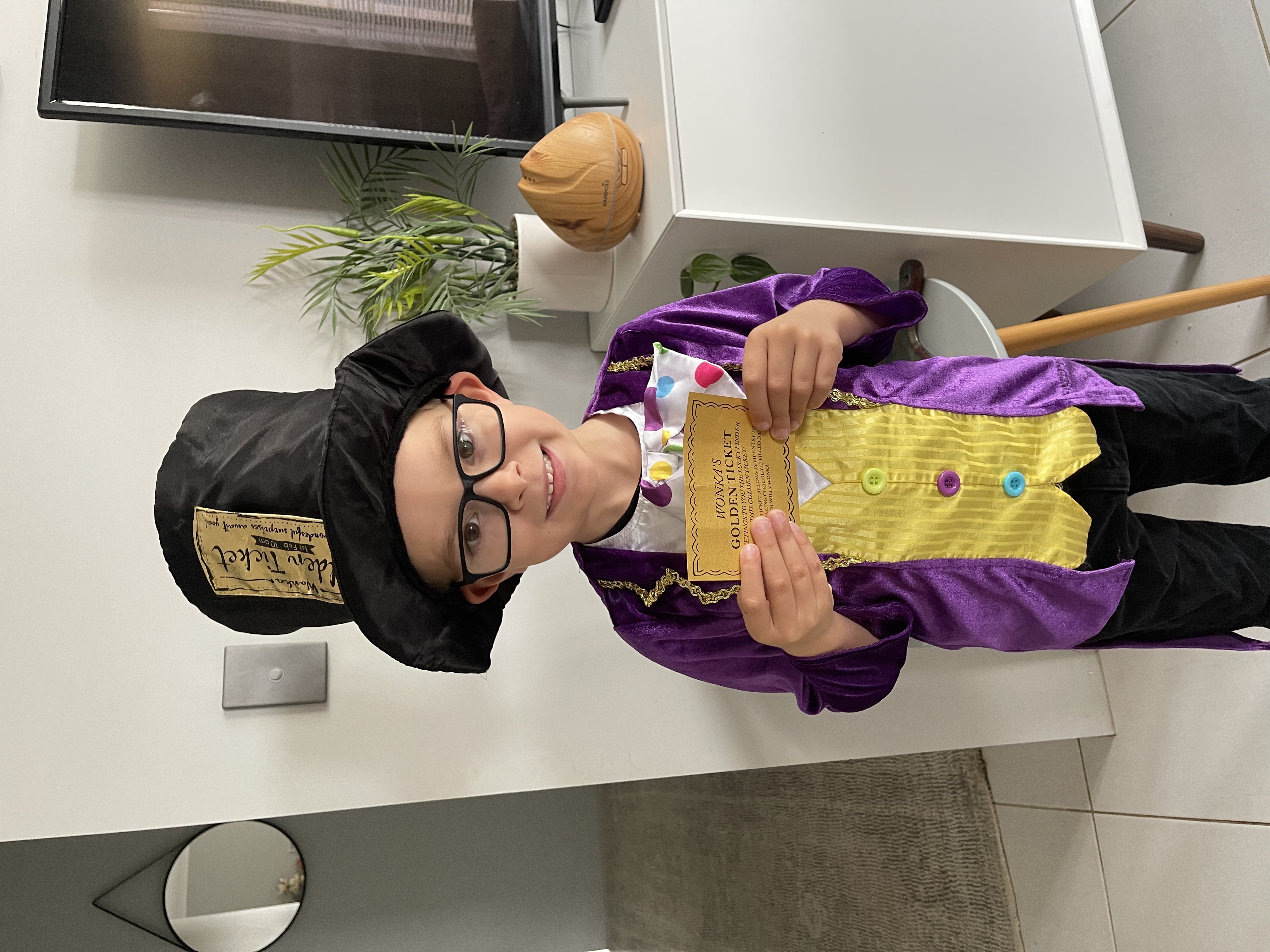 Boy dressed as Willy Wonka holding a golden ticket