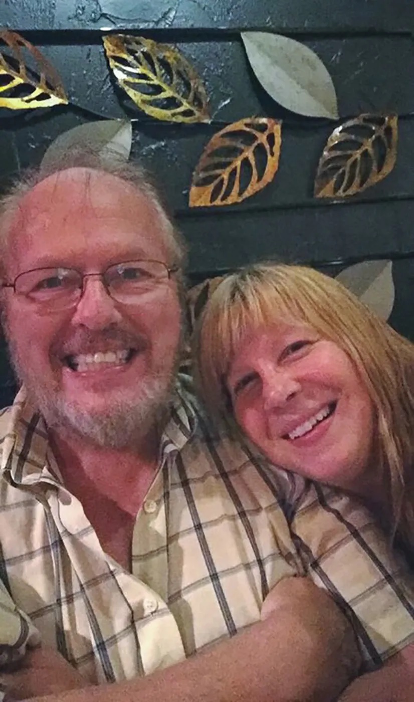 man wearing plaid shirt smiling, woman with fringe also smiling
